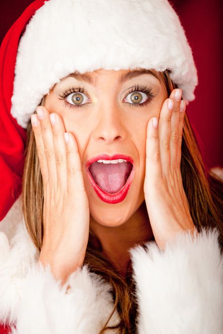 Portrait of a beautiful female Santa looking surprised over Christmas