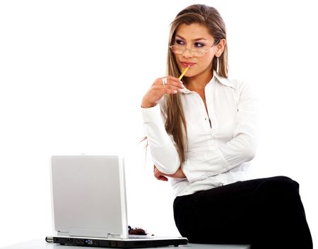business woman looking pensive while sitting on her desk with a laptop - isolated over white