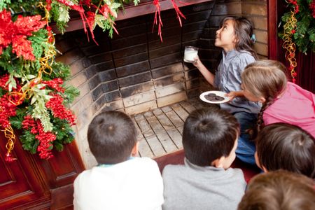 Kids waiting for Santa by the chimney with milk and cookies