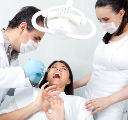 Woman visiting the dentist looking very frightened