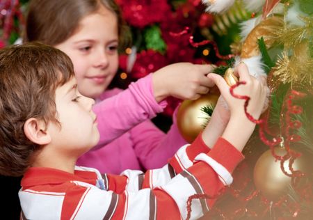 Happy kids hanging a ball on the Christmas tree