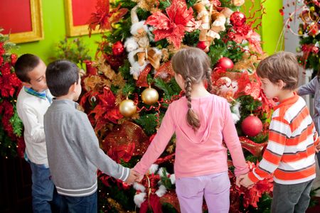 Kids around Christmas tree celebrating the winter holidays