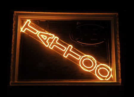 Neon sign in display window of tattoo parlor