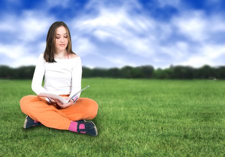 beautiful girl reading on the grass in a park