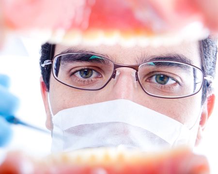 Male dentist working on teeth inside a mouth with an instrument