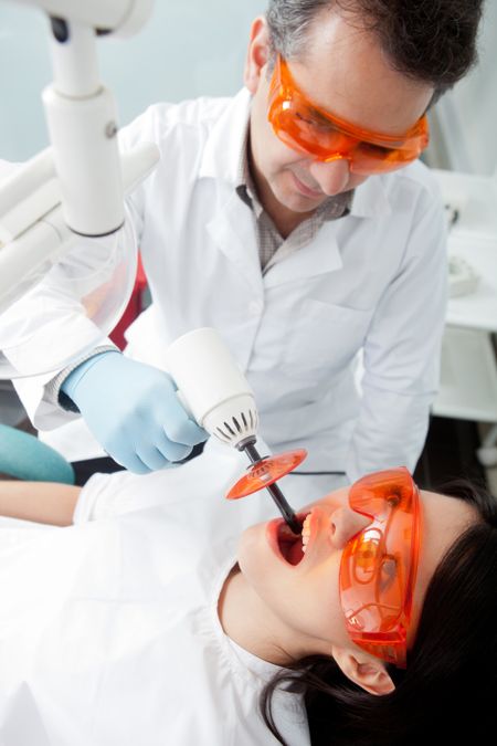 Dentist using laser light on a female patient