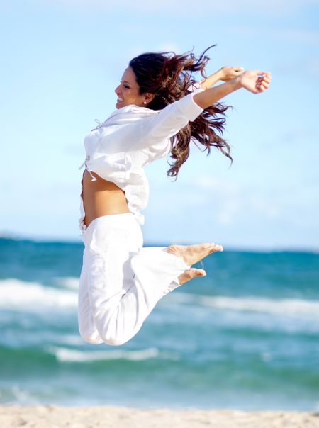 Happy woman enjoying her time at the beach and jumping