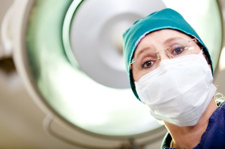 Female surgeon at an operating room wearing facemask and hat