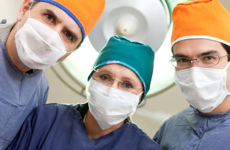 Group of surgeons at an operating room wearing facemasks and hats