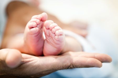 Tender picture of a man holding a baby's feet