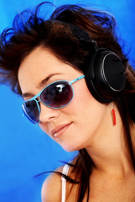beautiful woman listening and wearing sunglasses over a blue background