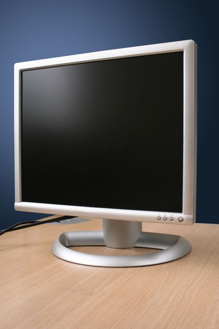 flatscreen monitor on a wooden desk over blue