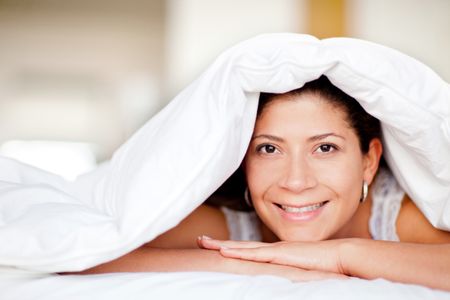 Woman portrait under the sheets looking happy