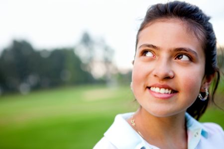 Portrait of a pensive young woman outdoors smiling