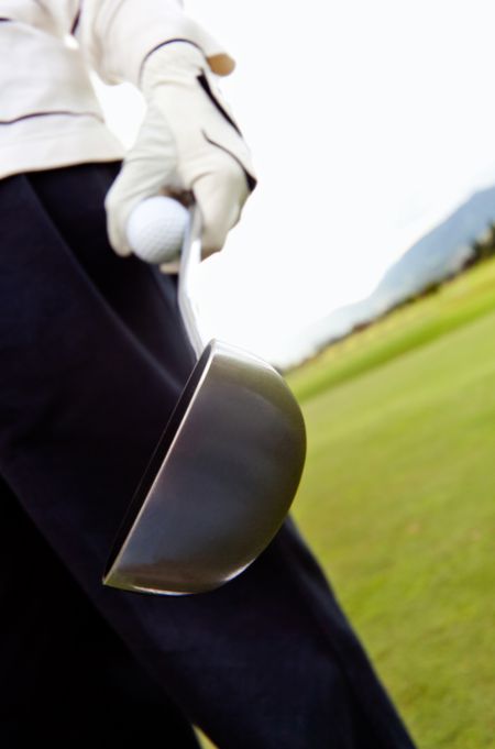 Golf player close-up on hand holding ball and club