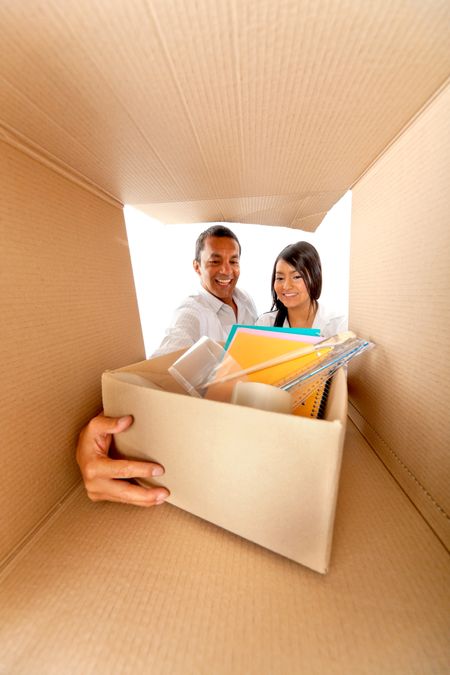 Couple packing in cardboard boxes to move house