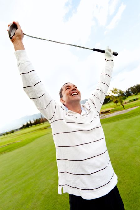 Man winning at golf with arms up at the course