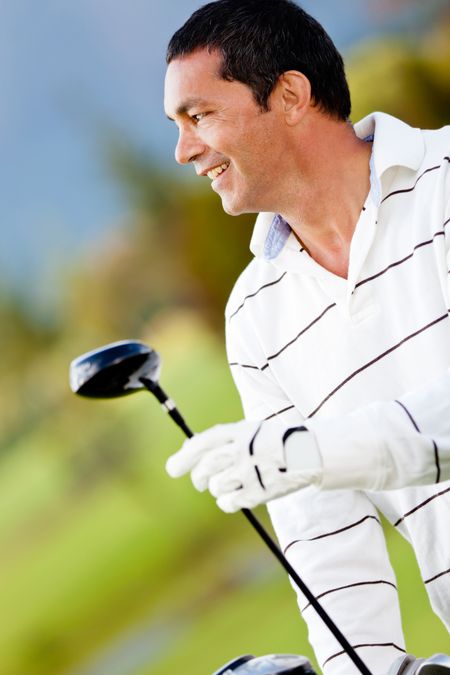 Male golf player holding a golf-club at the course