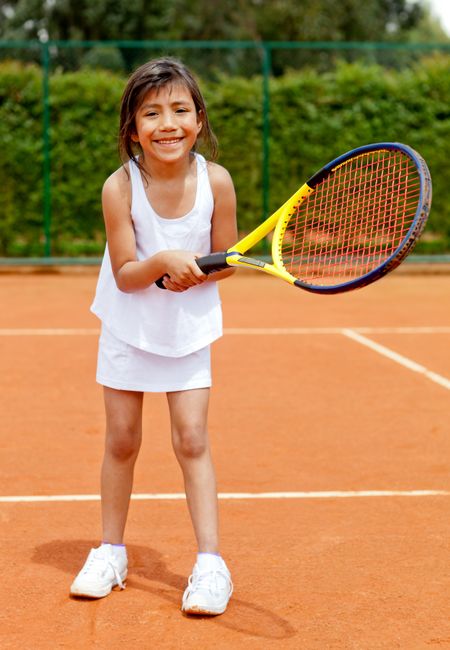 Girl playing tennis holding a racket at the court