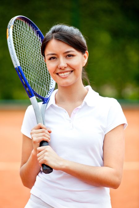 Woman playing tennis holding a racket and smiling
