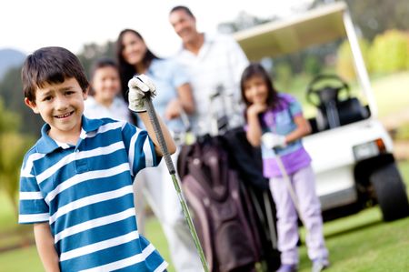 Boy playing golf with his family at the background