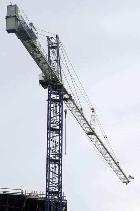 Tower crane with American flag at its far end, on a construction site for a high-rise building