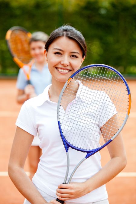 Woman playing doubles at tennis and smiling