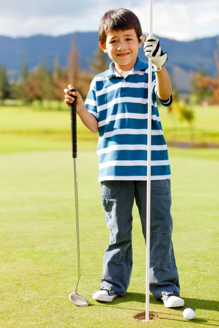 Boy at the course next to a hole playing golf