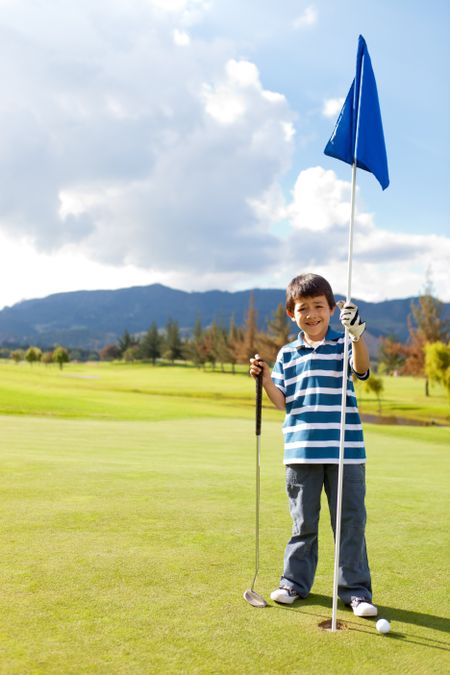 Boy with a golf flag in the hole at the course
