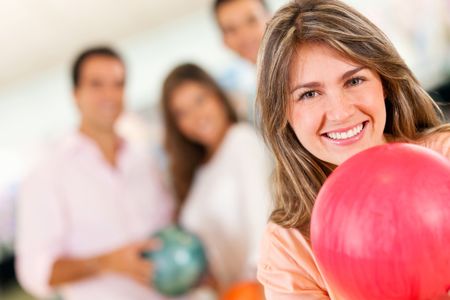 Beautiful woman bowling holding a ball with friends and smiling