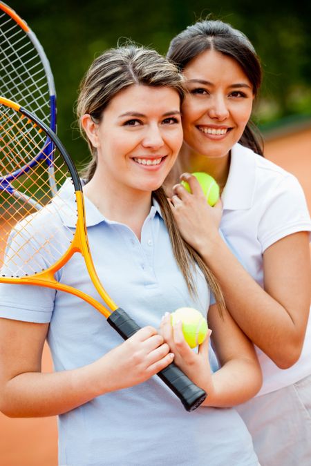 Beautiful female tennis players at the court smiling