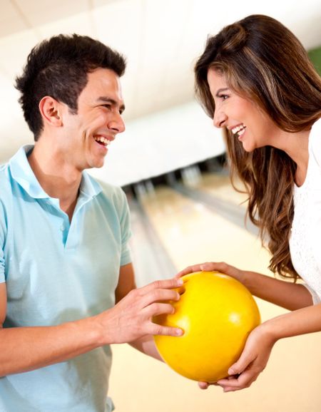 Couple going bowling for a date frirting and smiling