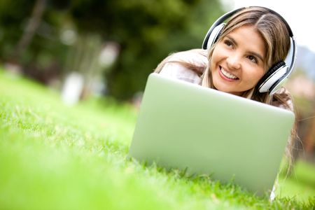 Woman downloading music in her laptop computer - outdoors