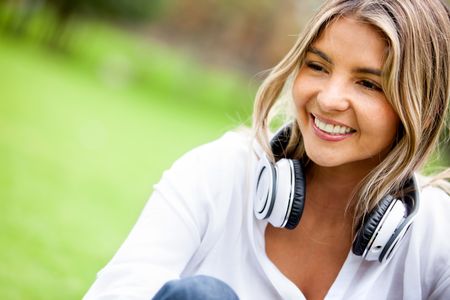 Casual woman relaxing outdoors with headphones around her neck