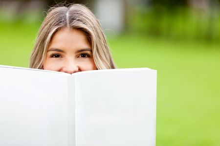 Beautiful female student holding a book outdoors