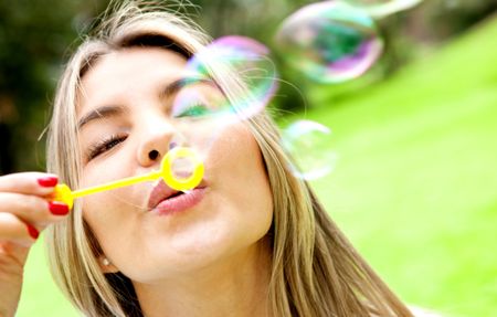 Woman blowing soap bubbles with a wand at the park