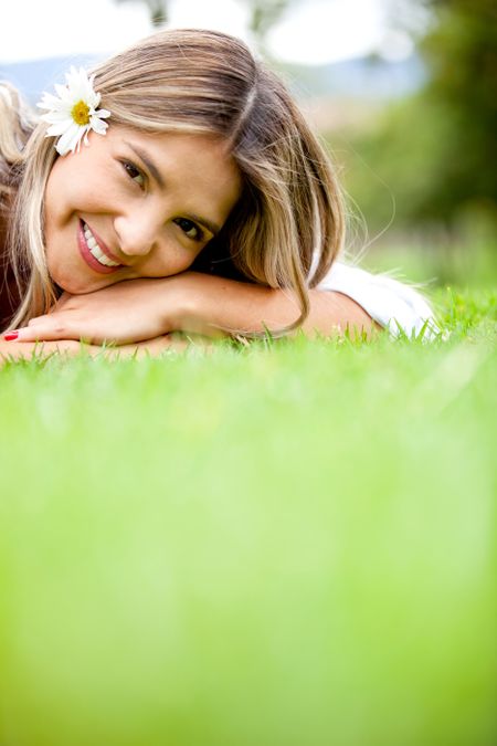 Cute woman with a dasiy on her head lying on the floor - outdoors