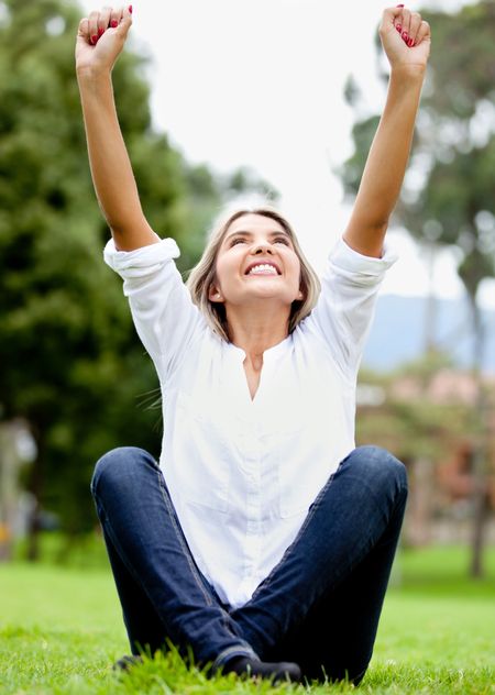 Happy woman outdoors with arms up and smiling