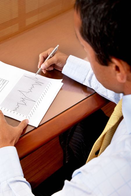 business man writing on a financial report where you can see the company growth