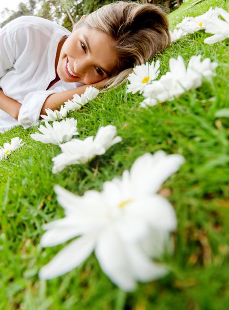 Beautiful woman lying on a floral garden full of daisies
