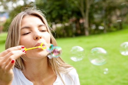 Young woman having fun blowing bubbles at the park