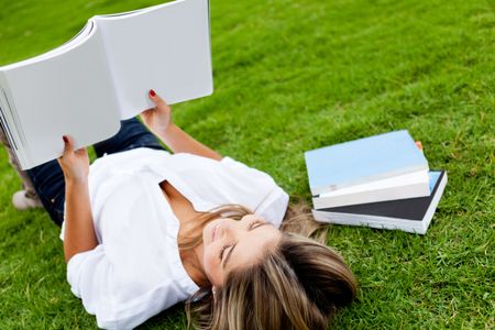 Woman reading a book lying at the park