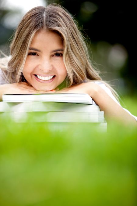Happy female student lying outdoors and smiling