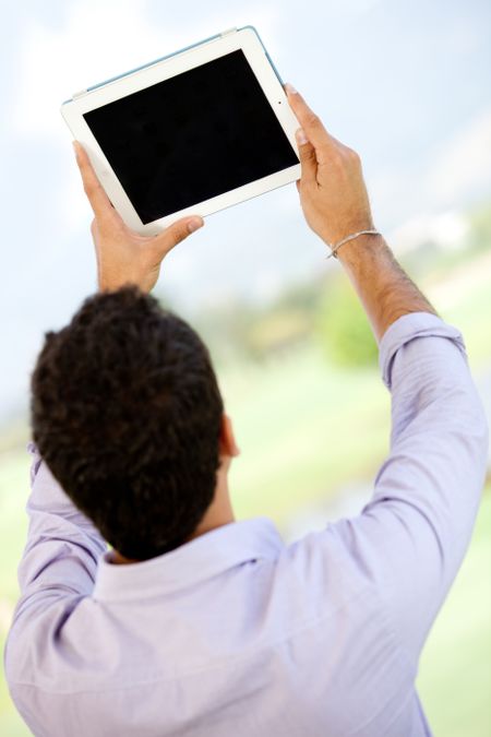 Man looking at the screen of a tablet computer - outdoors