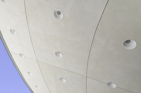 Curved ceiling of outdoor band shell with identical round recessed light fixtures