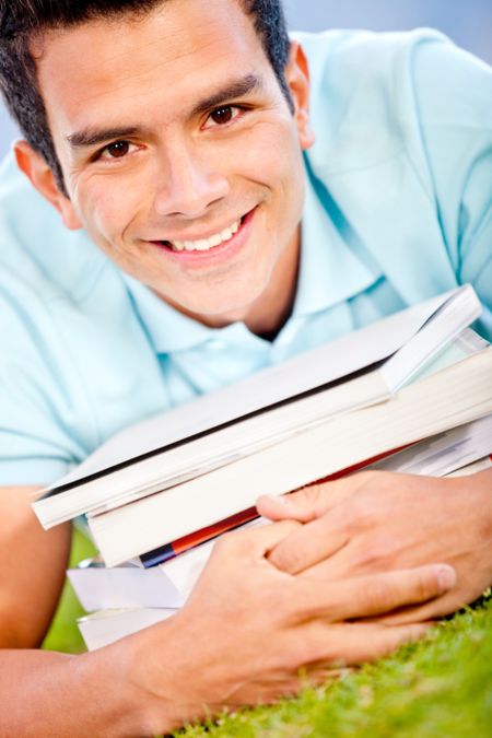 Happy male student with a pile of books