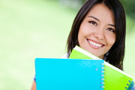 Beautiful woman holding notebooks outdoors - education portrait