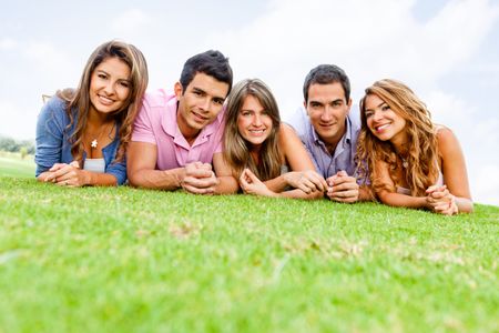 Group of young people lying outdoors smiling