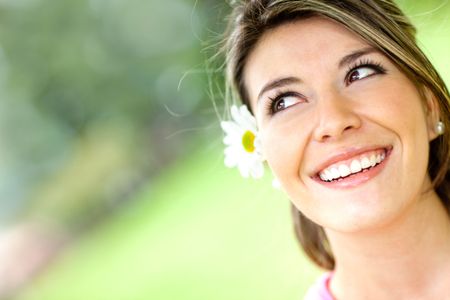 Cute pensive woman with a flower in her head and smiling