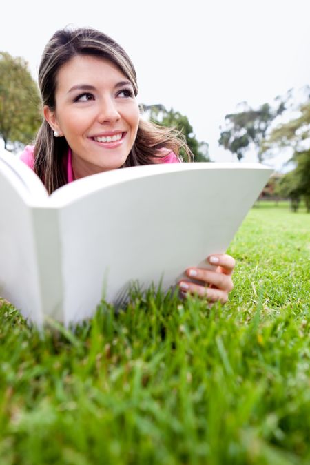 Beautiful woman reading a book outdoors and smiling